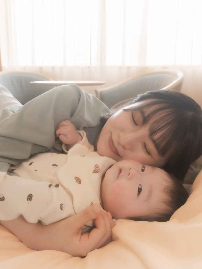 お母さんが赤ちゃんを抱っこしてベッドに横になっている姿