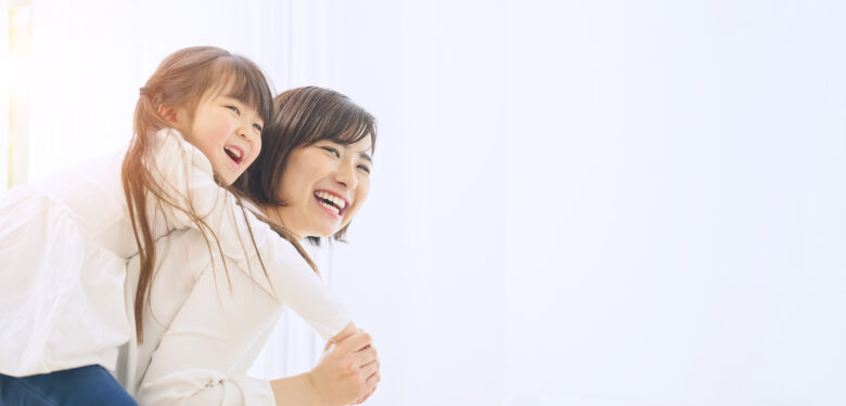 笑顔で娘を背中におんぶする母親