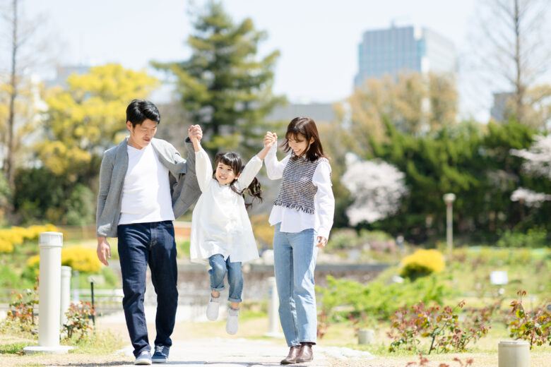 草原で両親が笑顔で子どもを両手で持ち上げている様子