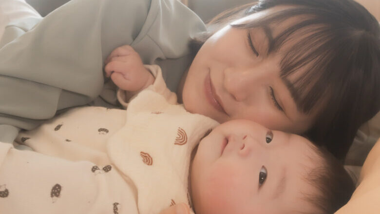 お母さんが赤ちゃんを抱っこしてベッドに横になっている姿